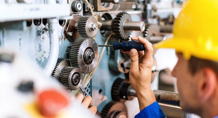 Blue collar worker or engineer working in industrial production plant, dealing with metal processing, hydraulic machinery, production lines and other processing industry machines. Image taken in Serbia, Europe.